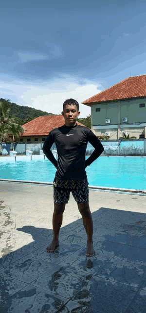 a man stands in front of a swimming pool wearing a nike shirt