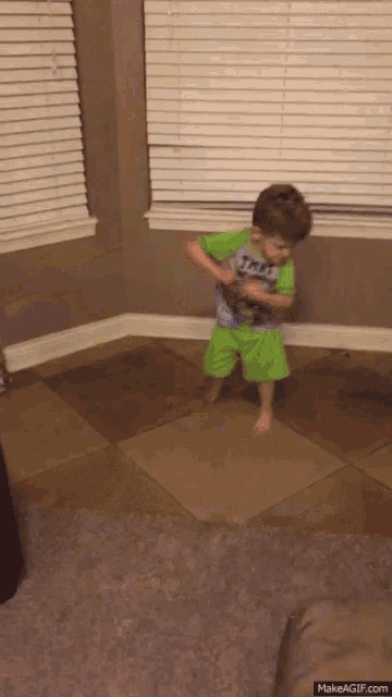 a young boy wearing a shirt that says ' spiderman ' on it is standing on a tiled floor