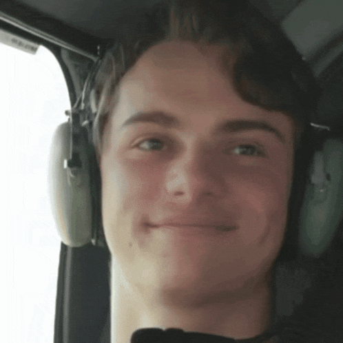a man wearing headphones looks at the camera with a smile on his face