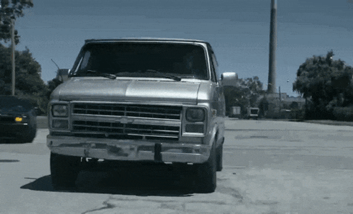 a silver van is parked in a parking lot with other cars