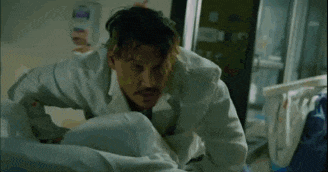 a man in a lab coat is kneeling down in a hospital bed .