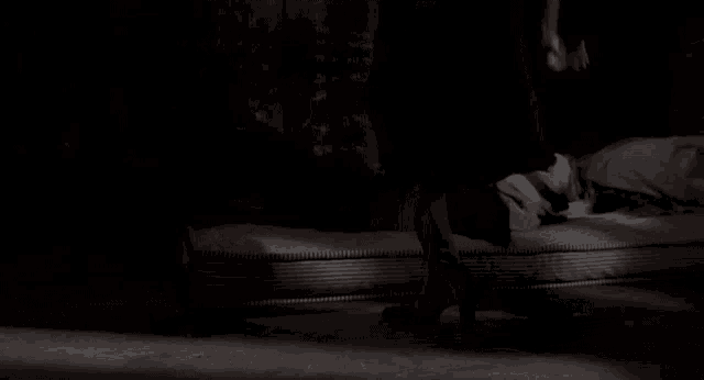 a woman is standing next to a man who is laying on a bed .