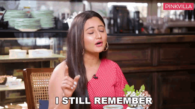 a woman is sitting at a table with a cup of coffee and says " i still remember "