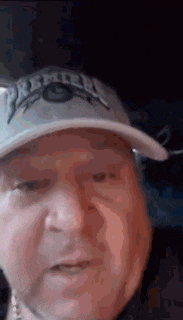 a close up of a man wearing a hat and a necklace .