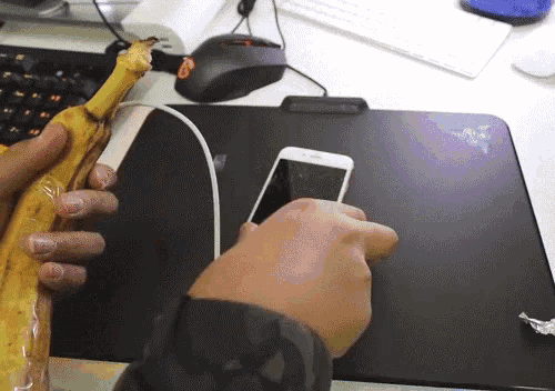 Homem usando uma banana como carregador de celular.