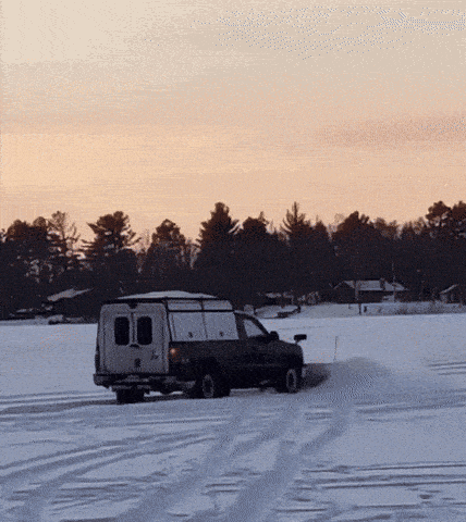 a truck is driving through a snowy field with a van on top