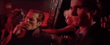 two men in suits are sitting next to each other in a dark room .