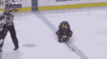 a hockey player is kneeling down on the ice with a puck .