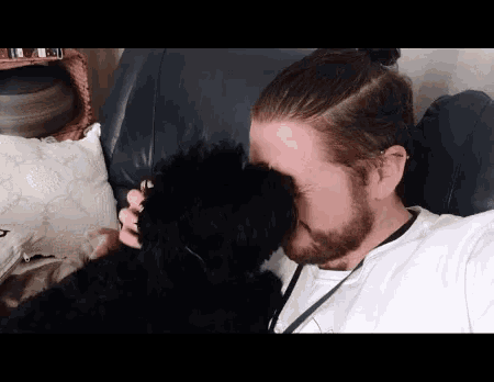 a man with a beard is sitting on a couch with his dog