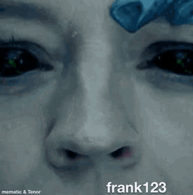 a close up of a person 's face with a blue object on their forehead and green eyes .