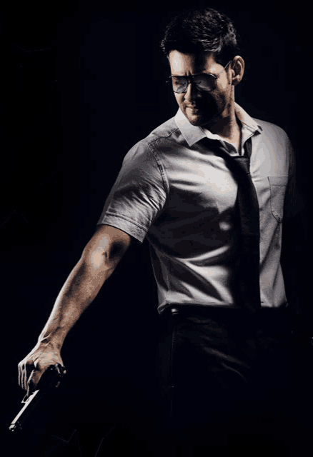 a man in a tie and sunglasses holds a gun
