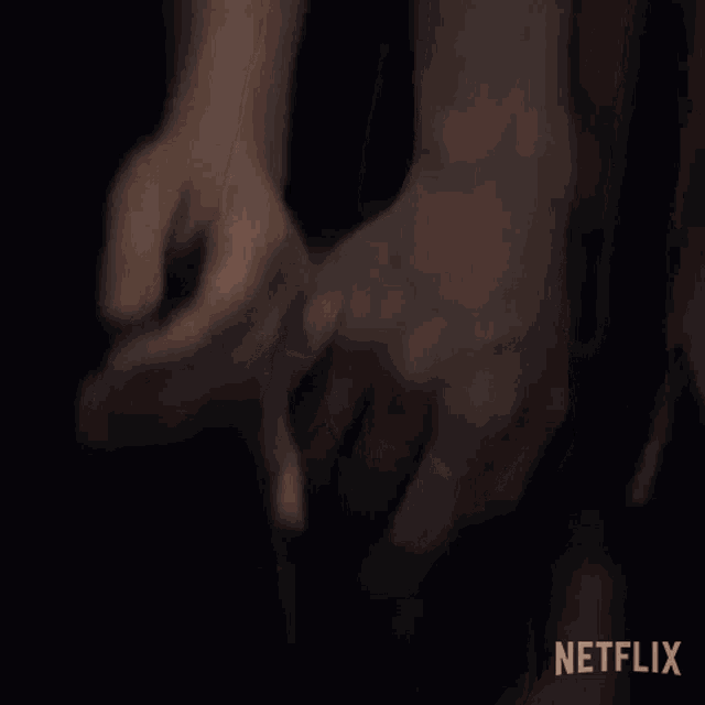a man is holding a woman 's hand in a dark room .