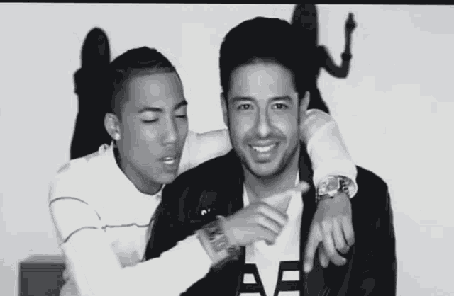 two men are posing for a picture and one has a watch on his wrist