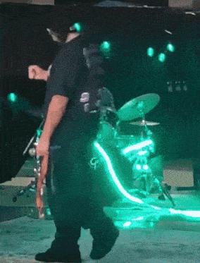 a man stands in front of a drum set with green lights