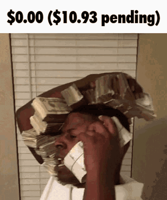 a man is holding a stack of money on his head and talking on a cell phone .