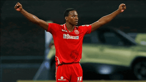 a man in a red shirt with the number 11 on it stands with his arms outstretched
