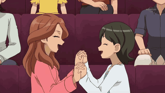 a cartoon of two women holding hands in a theatre with a tv channel in the corner