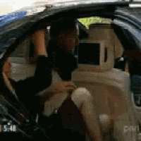 a man is sitting in the back seat of a car with a tv .