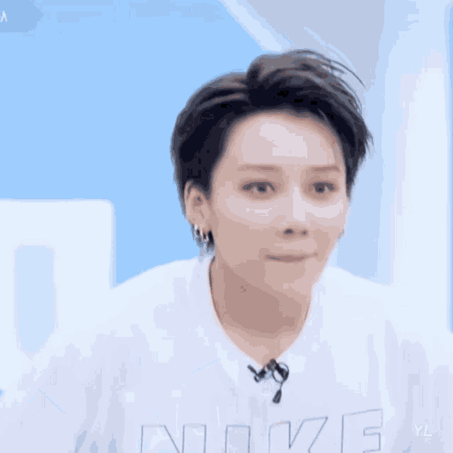 a woman with short hair is wearing a white t-shirt with the word love on it .