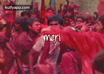 a man is surrounded by a crowd of people covered in red powder and the word meri is on the screen .