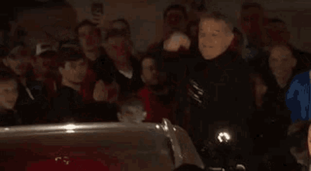 a group of people are standing around a car in a parking garage at night .