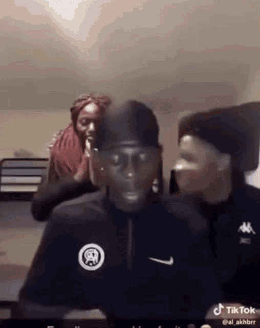 a man in a nike shirt is standing next to a woman in a red head scarf .