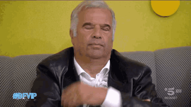 a man sitting on a couch with #gfvip written on the bottom of the screen