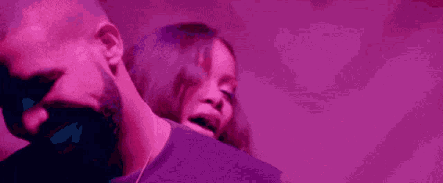 a man and a woman are standing next to each other in a purple light .