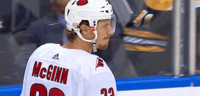 a hockey player wearing a white jersey with the name mcginn on the back