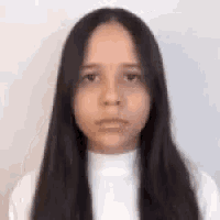 a young woman with long dark hair is wearing a white turtleneck .