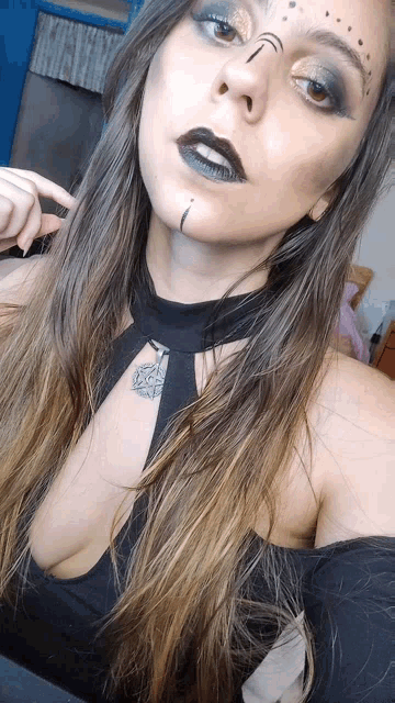 a woman with a tattoo on her forehead takes a selfie with her finger