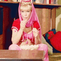 a woman in a pink and red outfit is sitting on a table