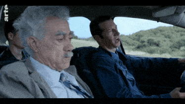 three men are sitting in a car with arte written on the bottom