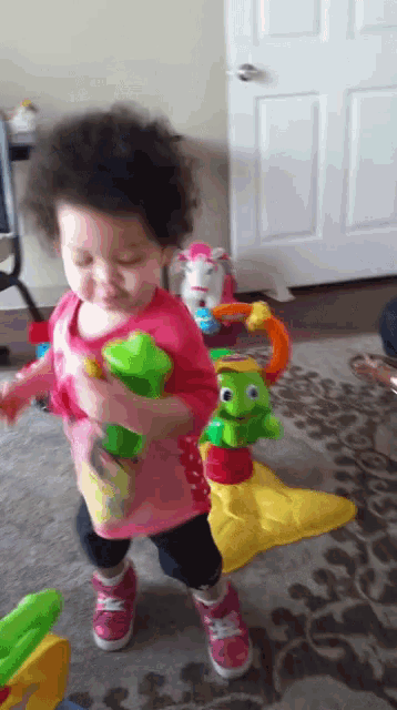 a little girl in a pink shirt playing with toys