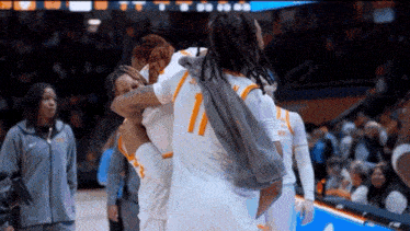a group of female basketball players are hugging each other on the court .