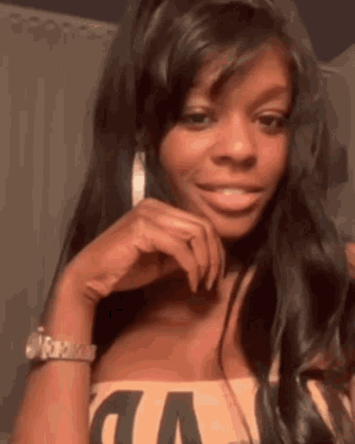 a woman with long hair is smiling and looking at the camera while wearing a watch and earrings .