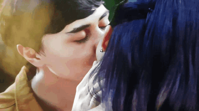 a man and a woman are kissing with blue hair