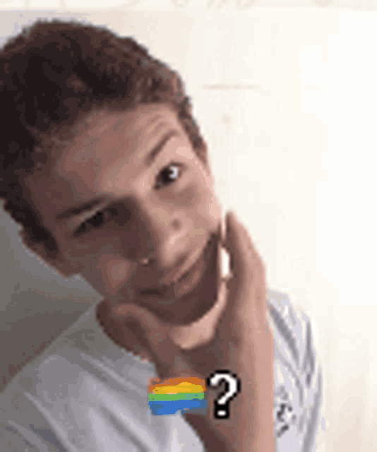 a young boy with a rainbow flag and a question mark on his arm is smiling .