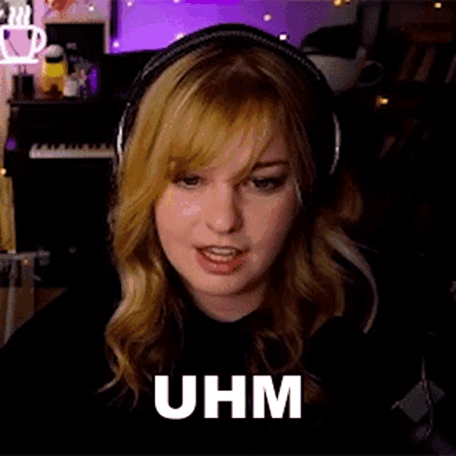 a woman wearing headphones is sitting in front of a microphone and making a funny face .
