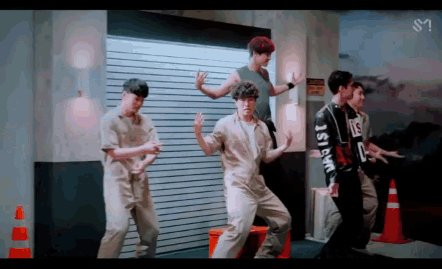 a group of young men are dancing in front of a garage door and a sign that says ' nct dream ' on it