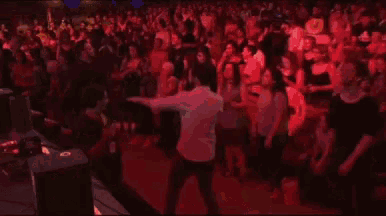 a man in a white shirt is dancing in front of a large crowd