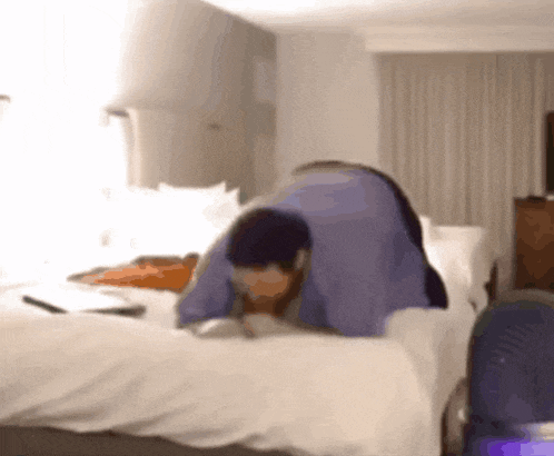 a man in a blue shirt is laying on a bed