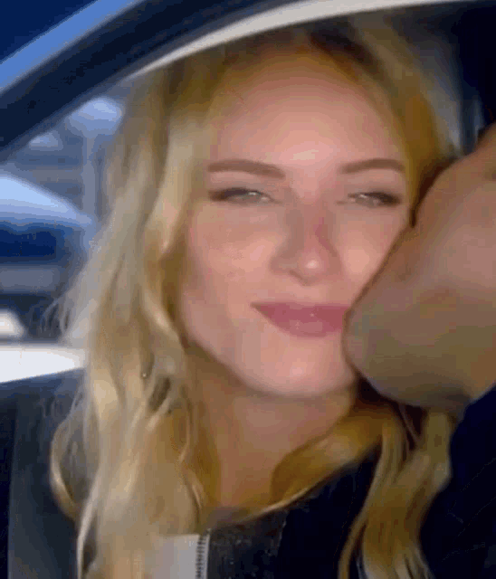 a man is kissing a woman on the cheek while sitting in a car .