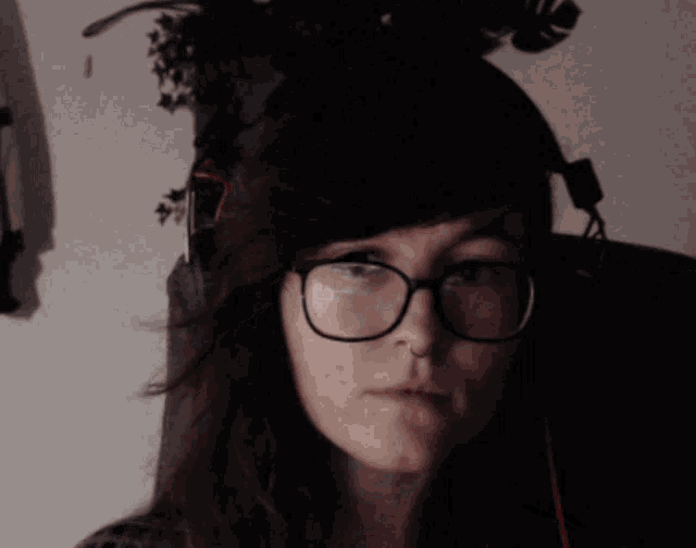 a woman wearing glasses and headphones has a nose ring