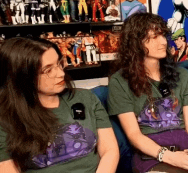 two women are sitting next to each other in front of a display of action figures