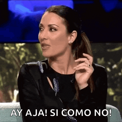 a woman in a black dress is sitting on a couch and saying ay aja ! si como no !