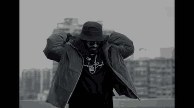 a black and white photo of a man wearing a hat and jacket