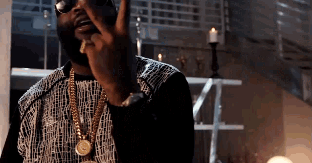 a man wearing sunglasses and a gold chain is making a funny face