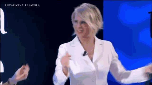 a woman in a white jacket is dancing on a television show .
