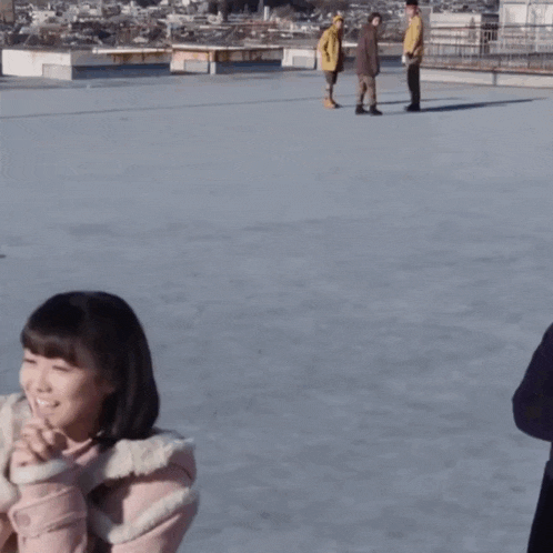 a group of people are standing on a rooftop and one of them is wearing a brown jacket